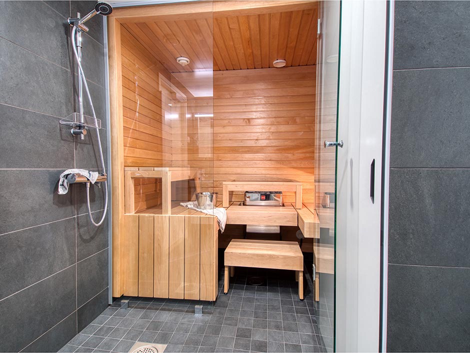 Hehkuvaa tyyliä: antrasiitinvärinen kylpyhuone ja sauna, jossa kokolasiseinä luo ylellisen tunnelman.